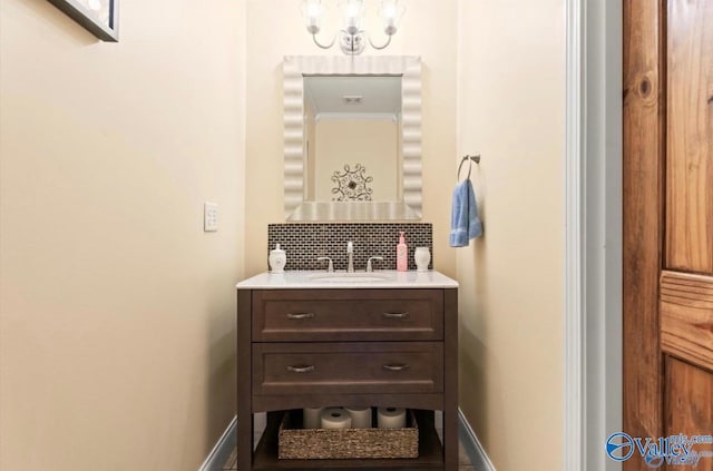 bathroom with an inviting chandelier, baseboards, backsplash, and vanity