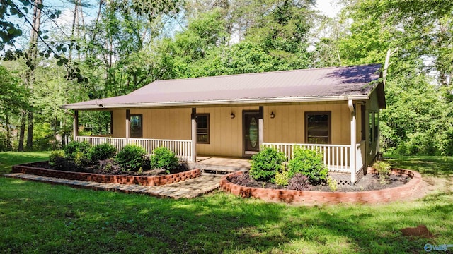 view of front of property featuring a porch, a front yard, and metal roof