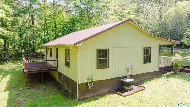 view of side of home with a yard, a wooden deck, and central AC unit