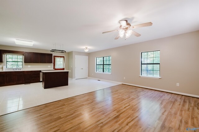 kitchen featuring dark brown cabinets, a center island, ceiling fan, and light wood-type flooring