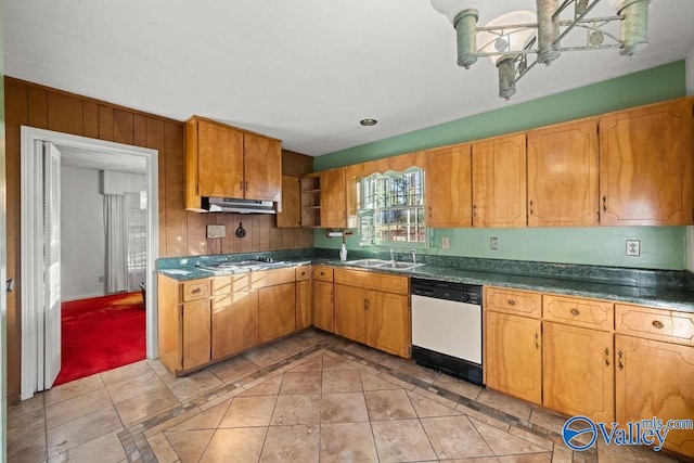 kitchen featuring sink, white dishwasher, wooden walls, stainless steel gas stovetop, and light tile patterned floors