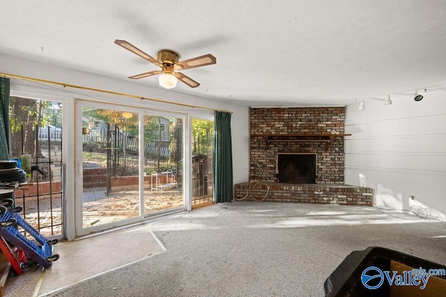 living room featuring carpet flooring, a textured ceiling, a brick fireplace, ceiling fan, and track lighting