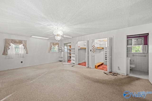 unfurnished room with a textured ceiling, carpet flooring, and plenty of natural light