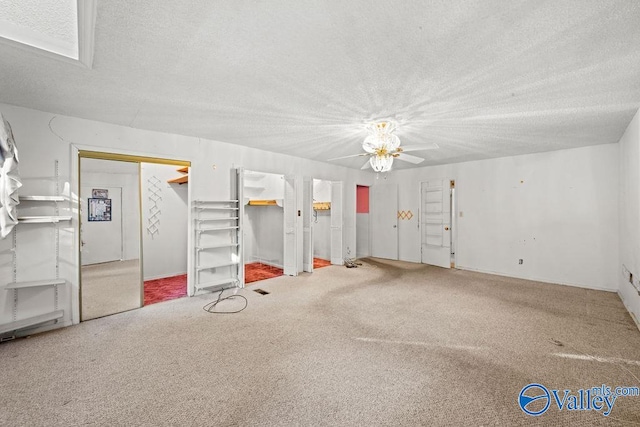 interior space with a skylight, ceiling fan, a textured ceiling, and carpet floors