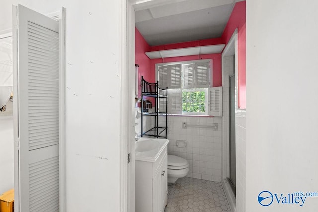 bathroom with tile walls, toilet, a shower with shower door, vanity, and tile patterned flooring