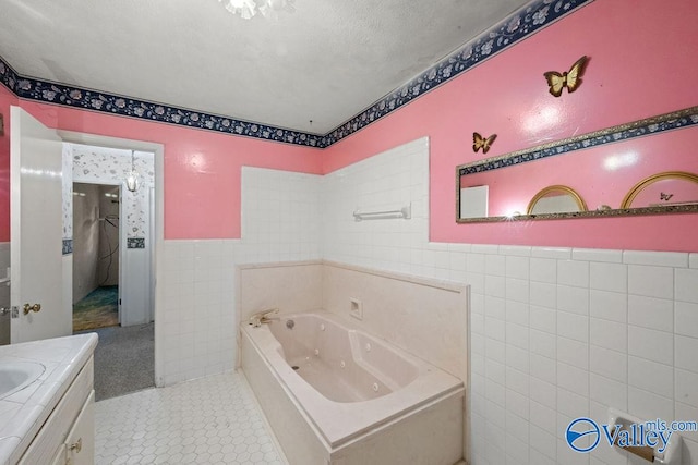 bathroom featuring a tub, a textured ceiling, tile walls, vanity, and tile patterned flooring