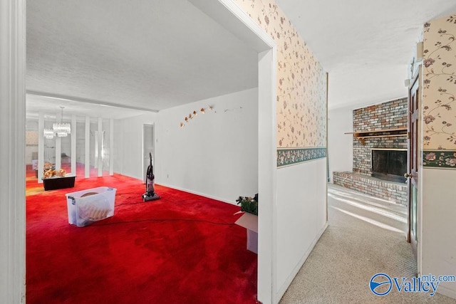 interior space featuring a notable chandelier, carpet, and a brick fireplace