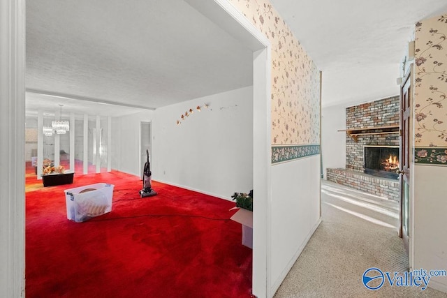 interior space featuring carpet, a brick fireplace, and a chandelier