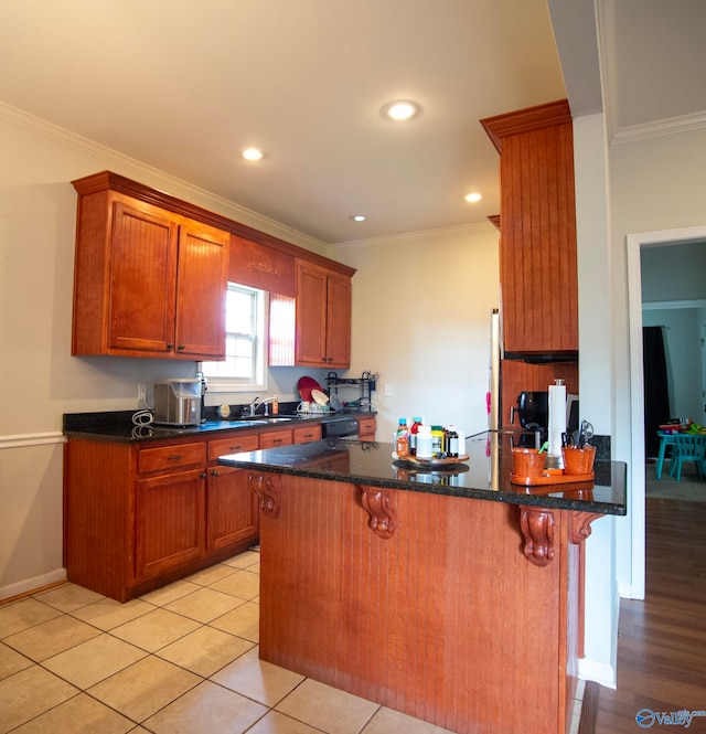 302 Meredith Dr, Muscle Shoals, AL 35661 - kitchen with ornamental molding, brown cabinets, a peninsula, a breakfast bar, and dark stone counters