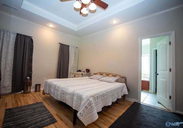 302 Meredith Dr, Muscle Shoals, AL 35661 - bedroom featuring a raised ceiling, crown molding, light wood-style floors, ensuite bathroom, and a ceiling fan