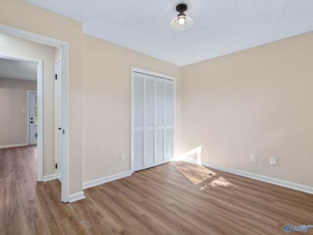 unfurnished bedroom featuring hardwood / wood-style floors, a closet, and a textured ceiling