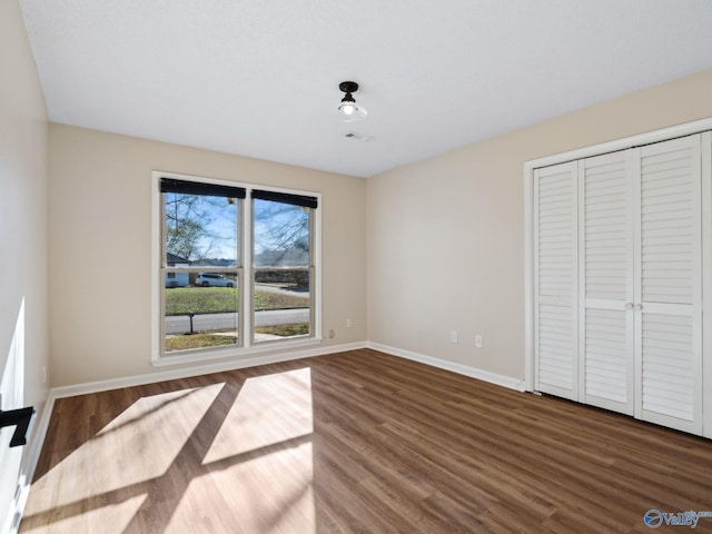 unfurnished bedroom with dark wood-type flooring and a closet