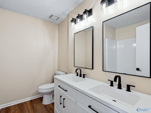 bathroom featuring vanity, toilet, hardwood / wood-style floors, and a textured ceiling