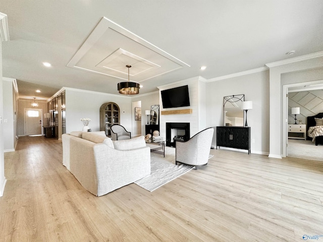 living room featuring light wood-type flooring, a large fireplace, baseboards, and ornamental molding