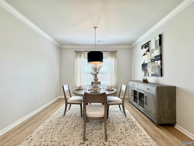 dining space featuring visible vents, baseboards, light wood-style floors, and crown molding