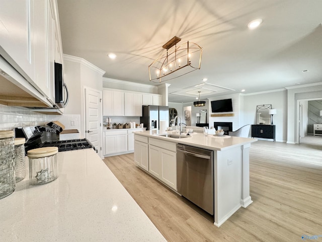 kitchen with open floor plan, light wood-type flooring, stainless steel appliances, white cabinetry, and a sink