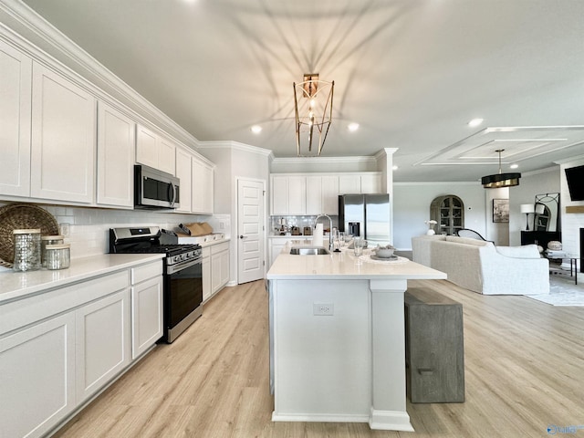 kitchen featuring light wood finished floors, crown molding, decorative backsplash, stainless steel appliances, and a sink