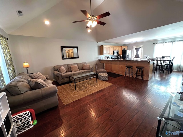 living area with dark wood-style floors, ceiling fan, visible vents, and high vaulted ceiling