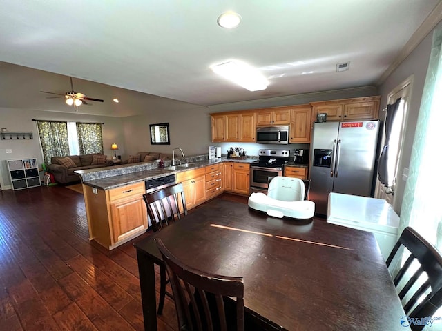 kitchen featuring a peninsula, a sink, visible vents, appliances with stainless steel finishes, and dark wood finished floors