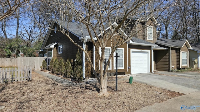 view of home's exterior featuring driveway, a shingled roof, a garage, and fence