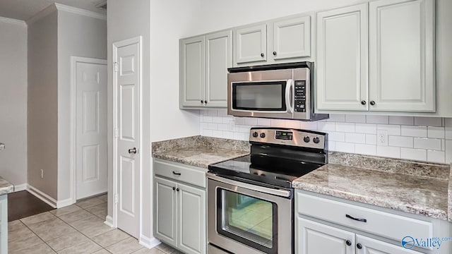 kitchen featuring light tile patterned floors, stainless steel appliances, light countertops, decorative backsplash, and ornamental molding