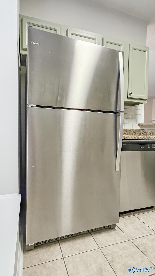 kitchen featuring stainless steel appliances, light stone countertops, decorative backsplash, and light tile patterned floors