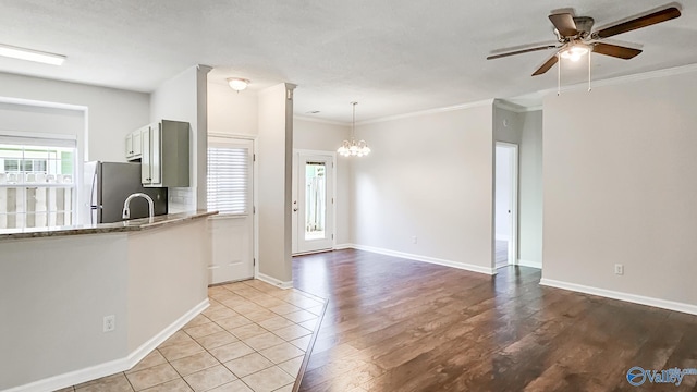 kitchen featuring light wood-style flooring, ornamental molding, decorative light fixtures, and freestanding refrigerator