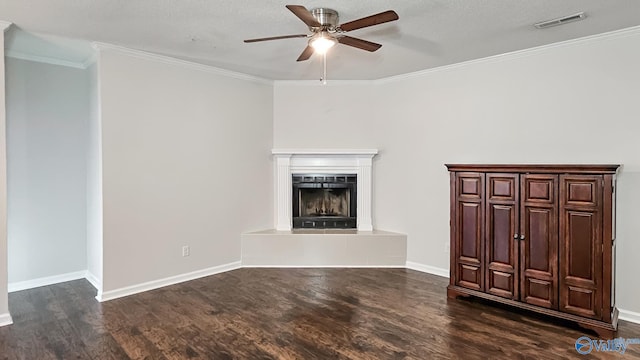 unfurnished living room with a fireplace with raised hearth, dark wood-style flooring, visible vents, and crown molding