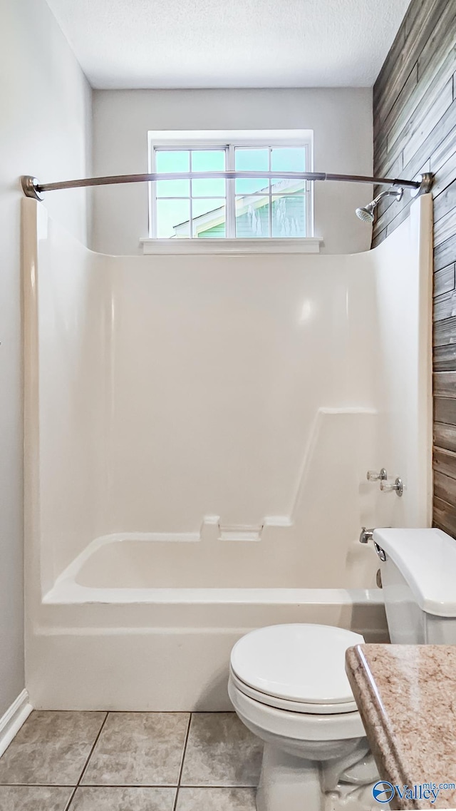 full bath with a textured ceiling, washtub / shower combination, toilet, and tile patterned floors