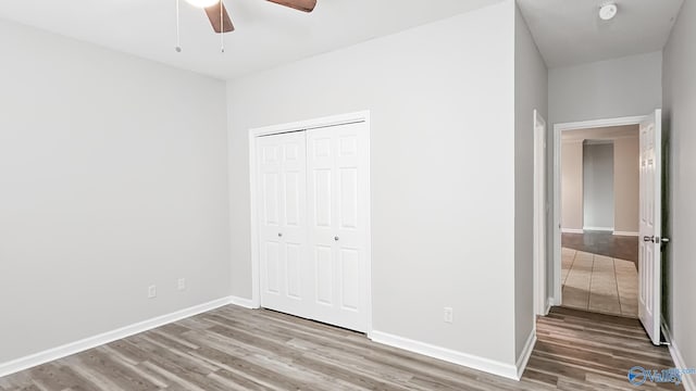 unfurnished bedroom with light wood-type flooring, a ceiling fan, baseboards, and a closet