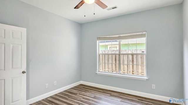 empty room with ceiling fan, wood finished floors, visible vents, and baseboards