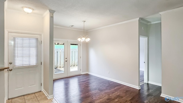 foyer featuring an inviting chandelier, wood finished floors, crown molding, and french doors