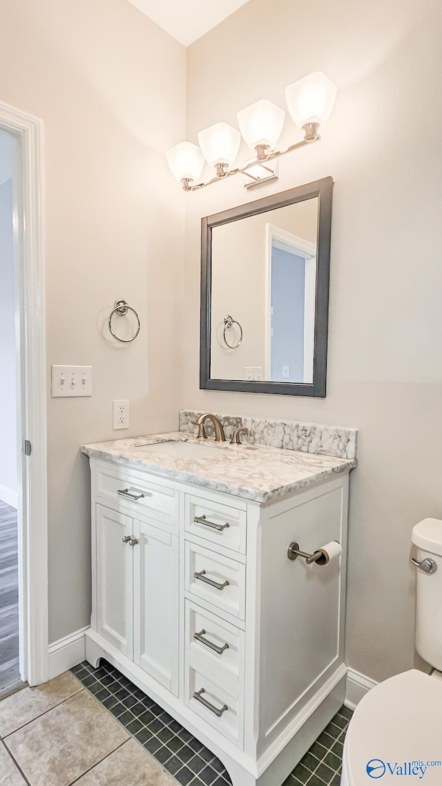 bathroom featuring tile patterned flooring, baseboards, vanity, and toilet