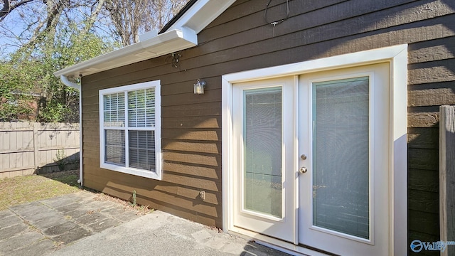 view of exterior entry with a patio area and fence