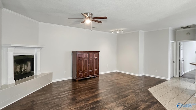 unfurnished living room with crown molding, a ceiling fan, a fireplace with raised hearth, and wood finished floors