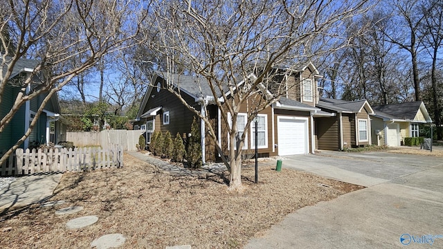 view of side of property with driveway, an attached garage, and fence