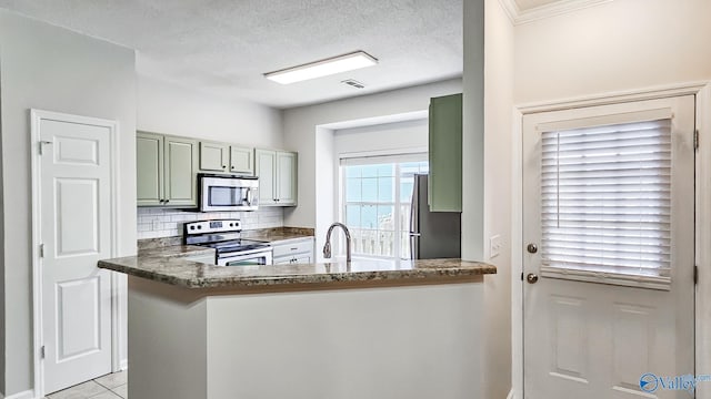 kitchen featuring decorative backsplash, appliances with stainless steel finishes, a textured ceiling, dark stone counters, and a peninsula