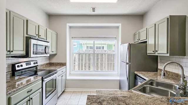 kitchen with tasteful backsplash, a textured ceiling, appliances with stainless steel finishes, and a sink