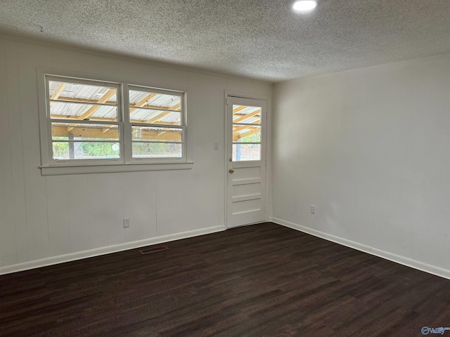 unfurnished room with dark wood-type flooring, a wealth of natural light, and a textured ceiling