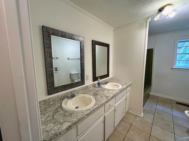 bathroom featuring tile patterned flooring, ornamental molding, a textured ceiling, vanity, and toilet