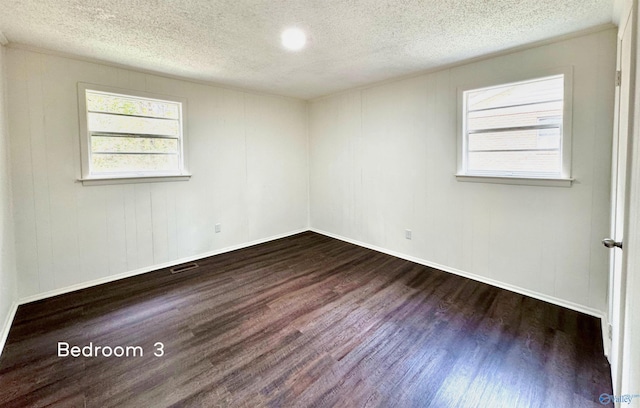 unfurnished room featuring dark hardwood / wood-style flooring and a textured ceiling