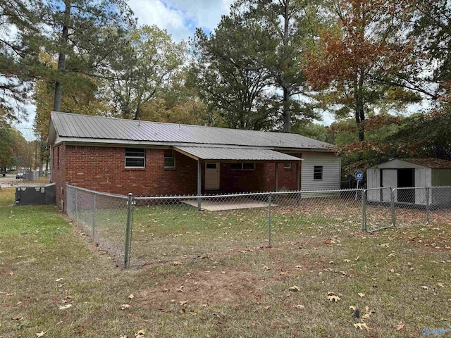 rear view of property with a storage unit and a lawn