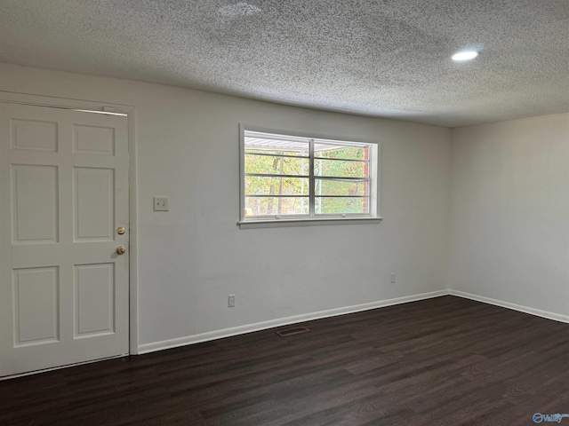 spare room with a textured ceiling and dark hardwood / wood-style floors