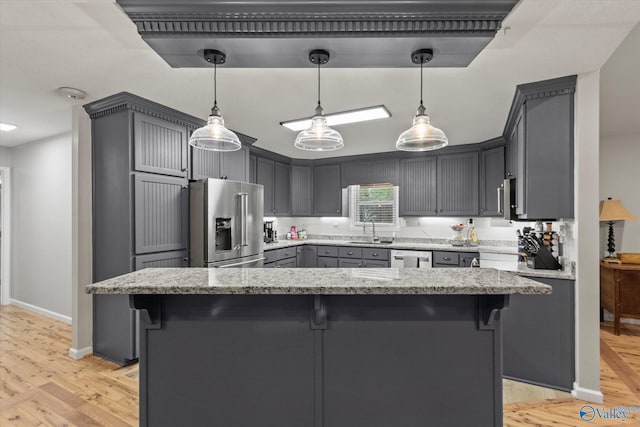 kitchen featuring light wood-type flooring, pendant lighting, stainless steel appliances, and light stone counters