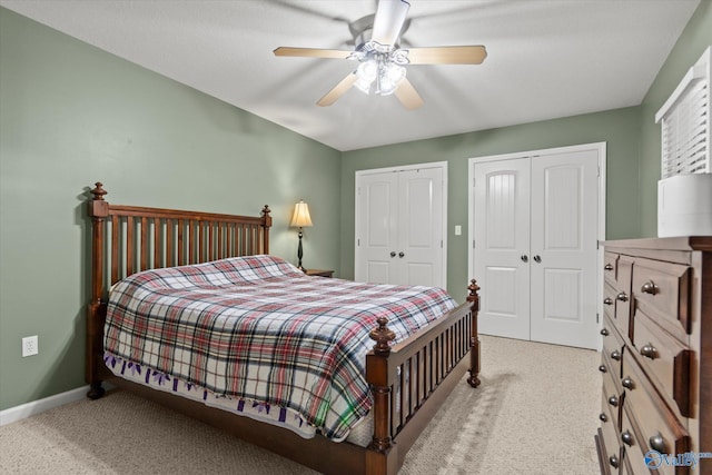 bedroom featuring light carpet, ceiling fan, and multiple closets