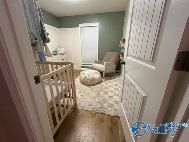 bedroom featuring hardwood / wood-style flooring and a crib