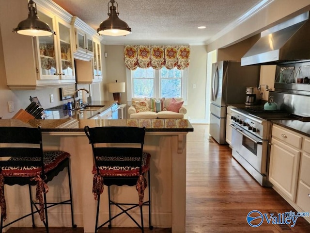 kitchen with wall chimney range hood, a breakfast bar area, stainless steel range, and kitchen peninsula