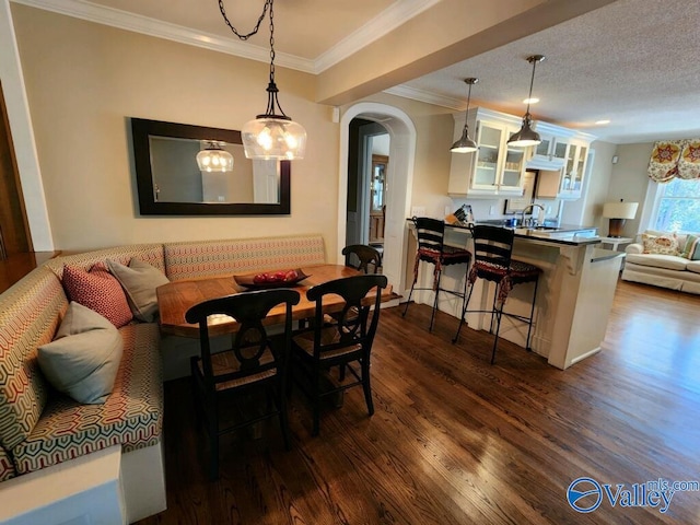 dining area featuring sink, dark hardwood / wood-style flooring, ornamental molding, breakfast area, and a textured ceiling