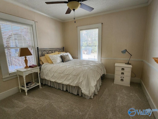 carpeted bedroom with ornamental molding, ceiling fan, and a textured ceiling