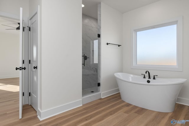 full bathroom featuring a freestanding tub, a stall shower, and wood finished floors